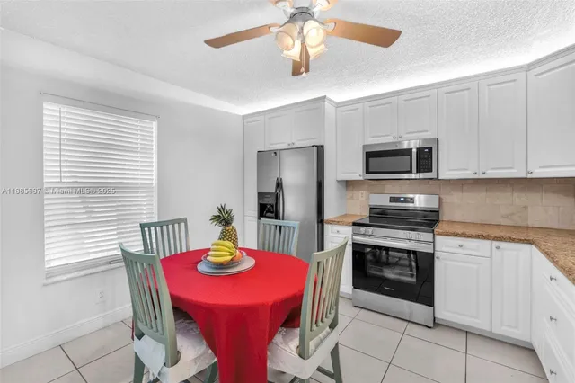 a kitchen with stainless steel appliances granite countertop a dining table chairs microwave and sink