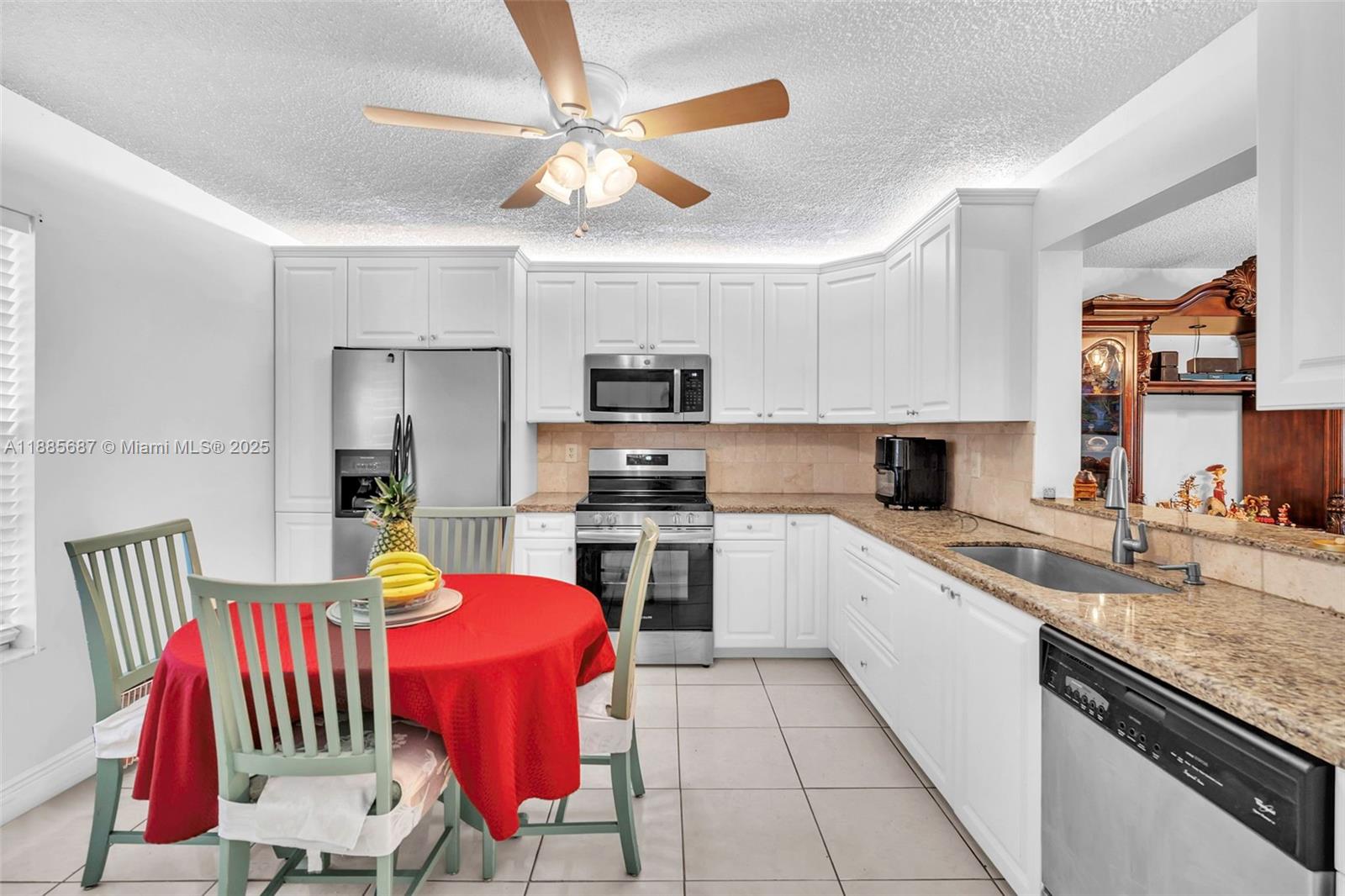 150 South Hollybrook Terrace, Unit 101 Pembroke Pines, FL 33025 - Photo 8 of 31 a kitchen with stainless steel appliances granite countertop a sink dishwasher a stove a refrigerator with a dining table and chairs