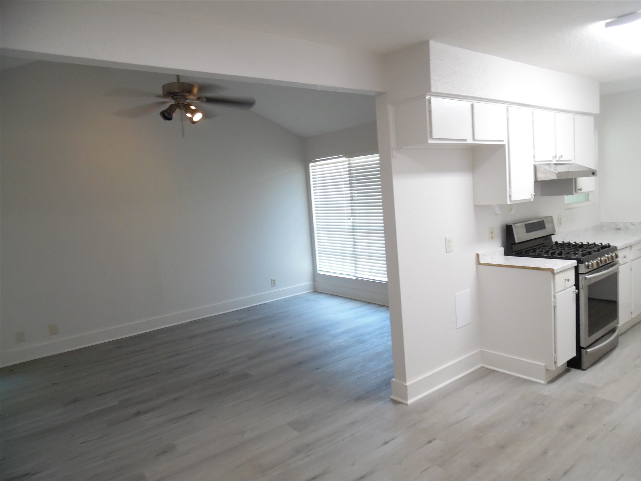 7400 Dixie Drive, Unit B Austin, TX 78744 - Photo 9 of 15 Open-concept living space featuring wood-finish flooring, a vaulted ceiling, and a ceiling fan with integrated lighting