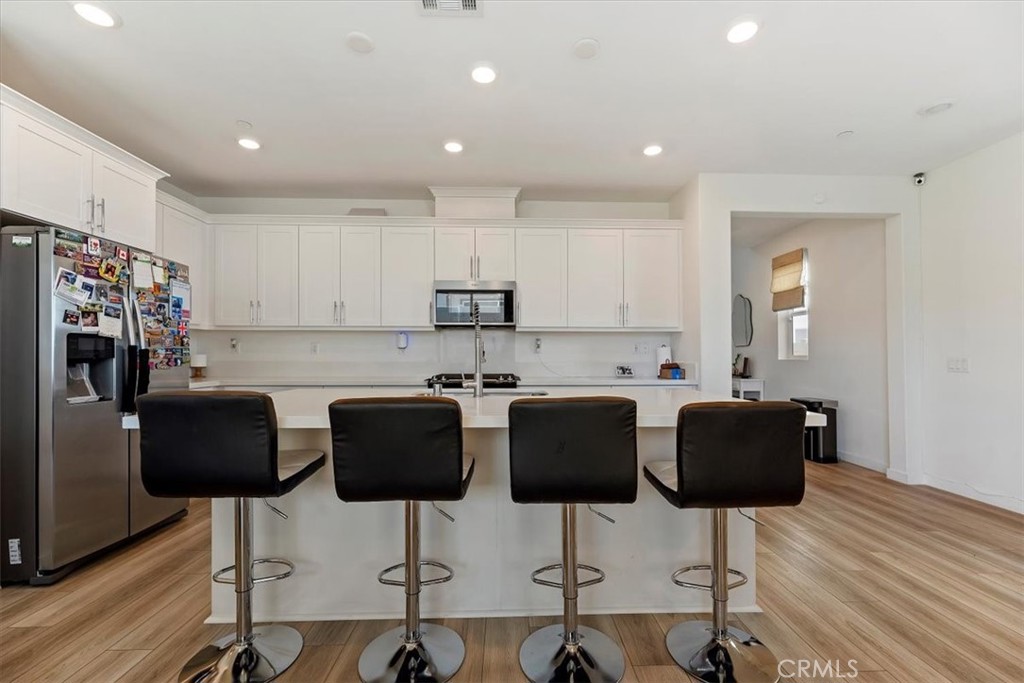 20911 Jennings Way Newhall, CA 91321 - Photo 13 of 50 a kitchen with stainless steel appliances kitchen island granite countertop a dining table chairs and a refrigerator
