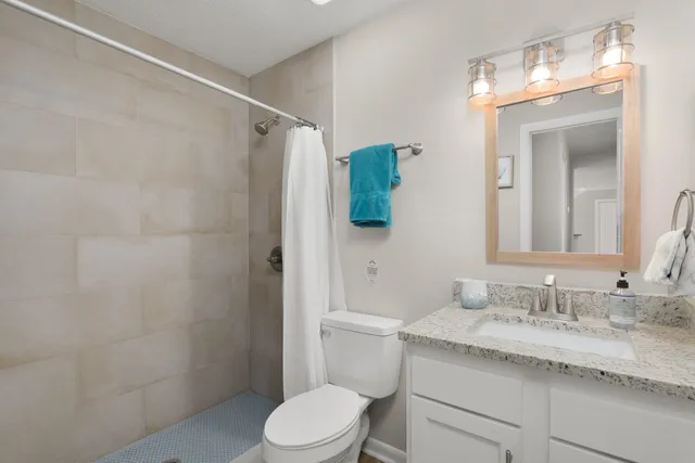 a bathroom with a granite countertop sink toilet and shower