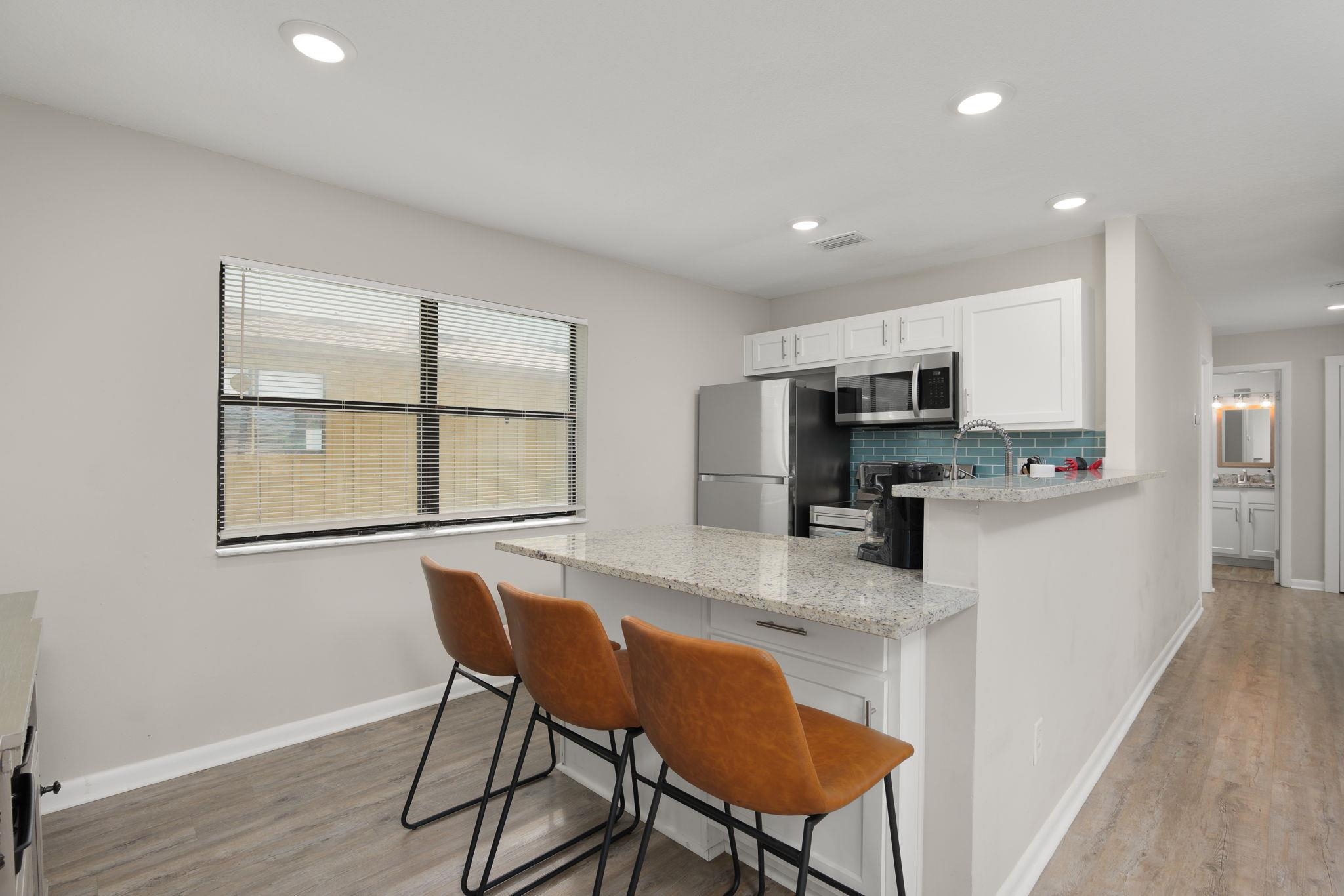 16 Ewing Street St. Augustine Beach, FL 32080 - Photo 20 of 55 a kitchen with stainless steel appliances granite countertop a stove a refrigerator a microwave a dining table and chairs with wooden floor