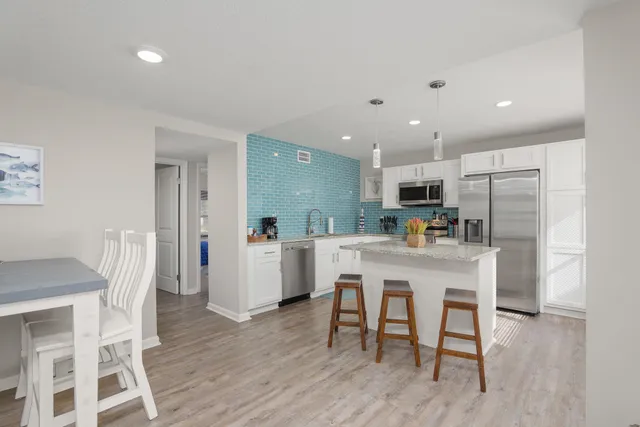 a kitchen with stainless steel appliances a dining table chairs and wooden floor