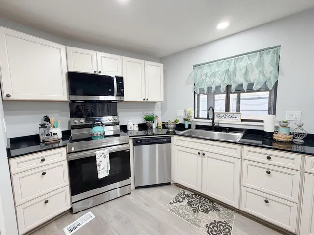 a kitchen with granite countertop white cabinets sink and stainless steel appliances