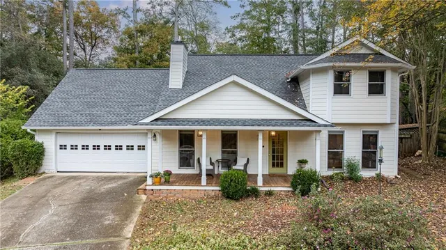 a view of a house with a yard plants and large tree