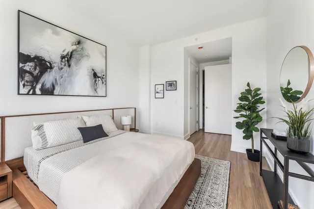 a bedroom with a large bed and a potted plant