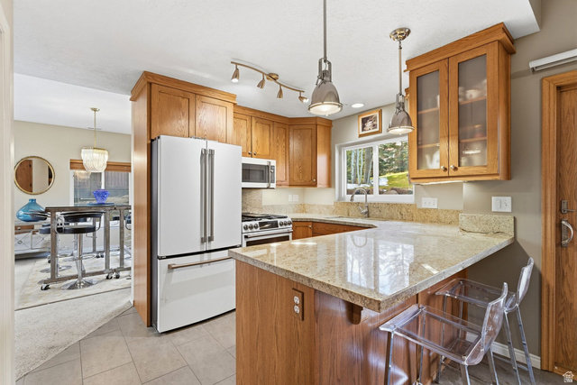 7930 Mustang Loop Road Park City, UT 84098 - Photo 5 of 23 Kitchen featuring a kitchen bar, stainless steel appliances, light stone countertops, wood finish cabinetry, and a peninsula