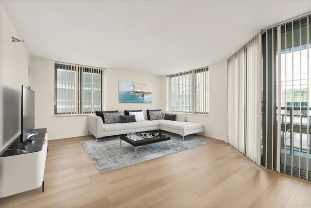 a living room with furniture wooden floor and a large window