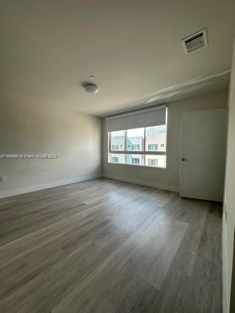 2561 Northeast 193rd Street, Unit 1207 Miami, FL 33180 - Photo 10 of 21 an empty room with wooden floor and windows