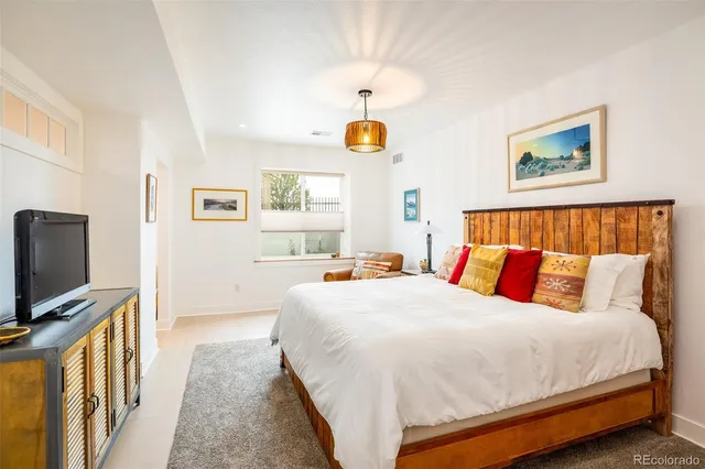 a bedroom with a bed a flat screen tv and paintings on the wall