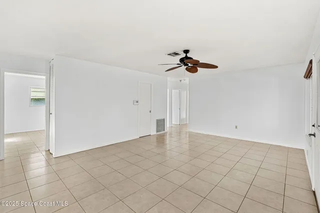 a view of an empty room and chandelier fan