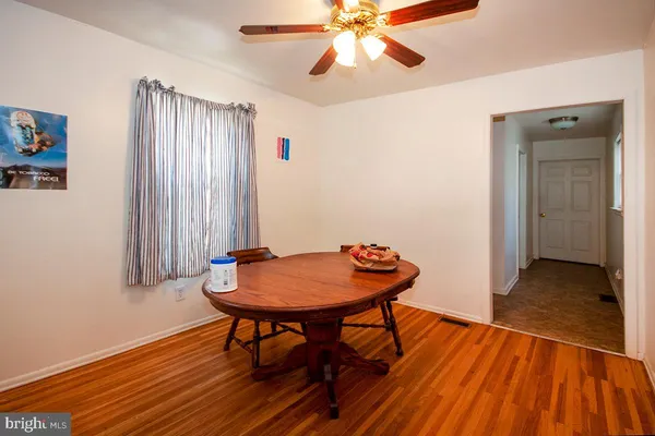 a dining room with wooden floor and a chandelier fan