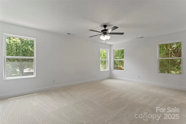 an empty room with windows and ceiling fan