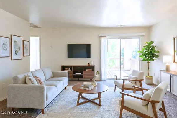 a living room with furniture a flat screen tv and a large window
