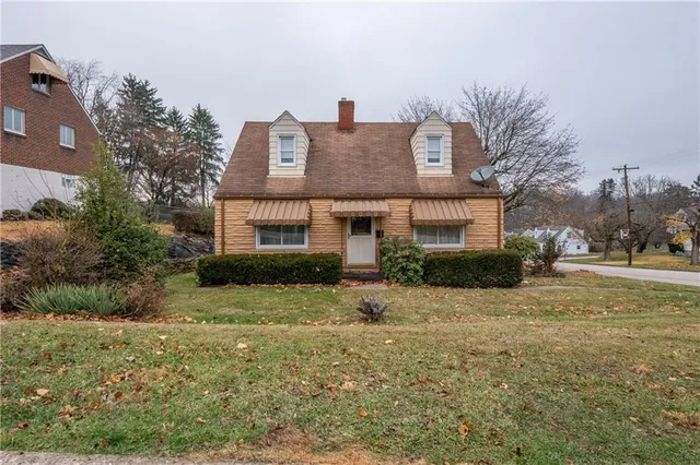 a front view of a house with a yard and trees