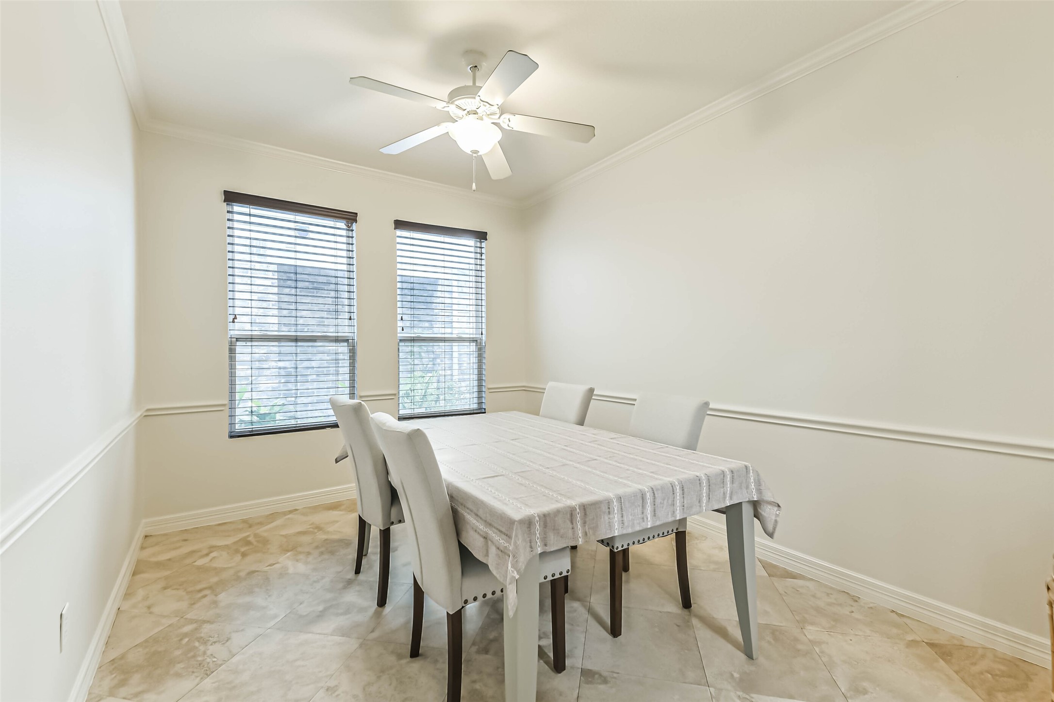 22538 Goss Spring Court Spring, TX 77373 - Photo 15 of 36 This dining area features a clean, bright design with neutral walls, a ceiling fan, and tiled flooring. Two large windows provide natural light, complementing the elegant table and chairs, creating a welcoming space for meals.