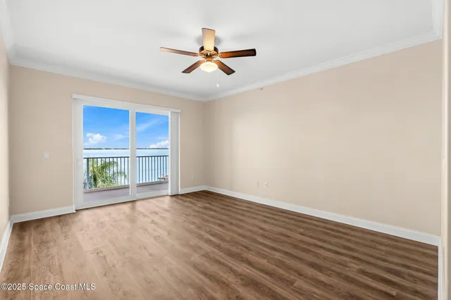 an empty room with wooden floor fan and windows