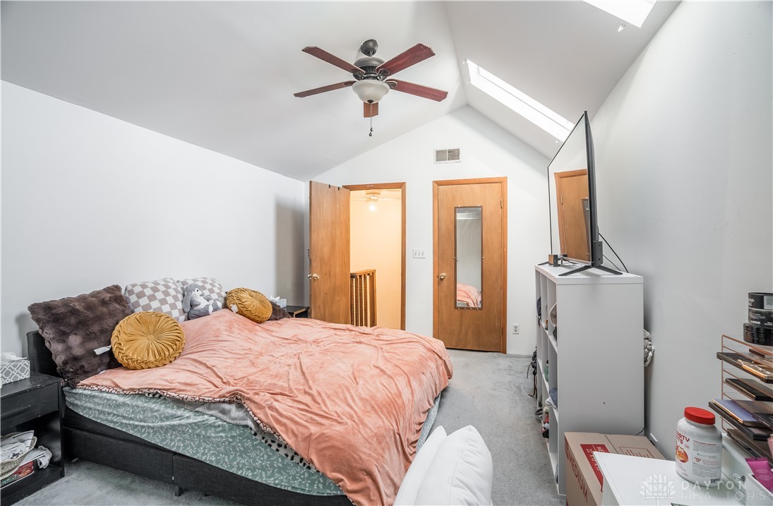 220 Racer Street Troy, OH 45373 - Photo 22 of 33 This spacious bedroom features vaulted ceilings, skylights, and carpeted floors, creating an inviting and airy atmosphere.
