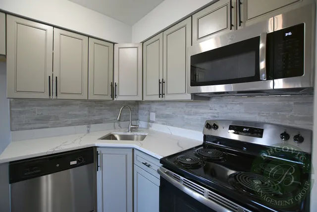 a kitchen with stainless steel appliances granite countertop white cabinets and black stove top oven with granite countertops
