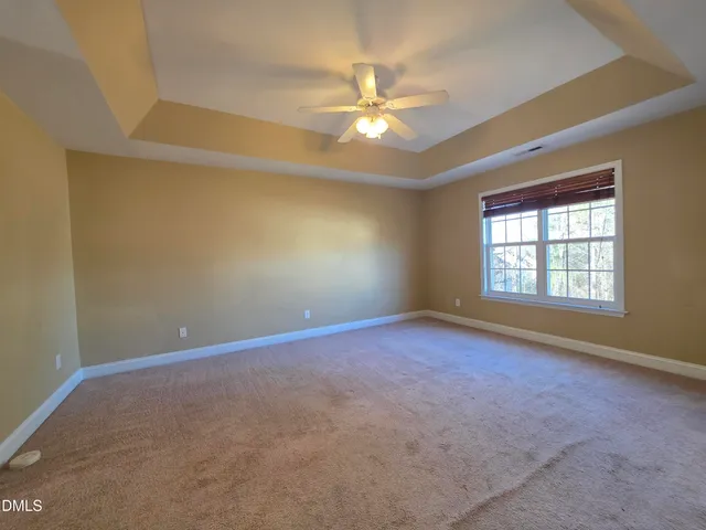 an empty room with windows and chandelier fan