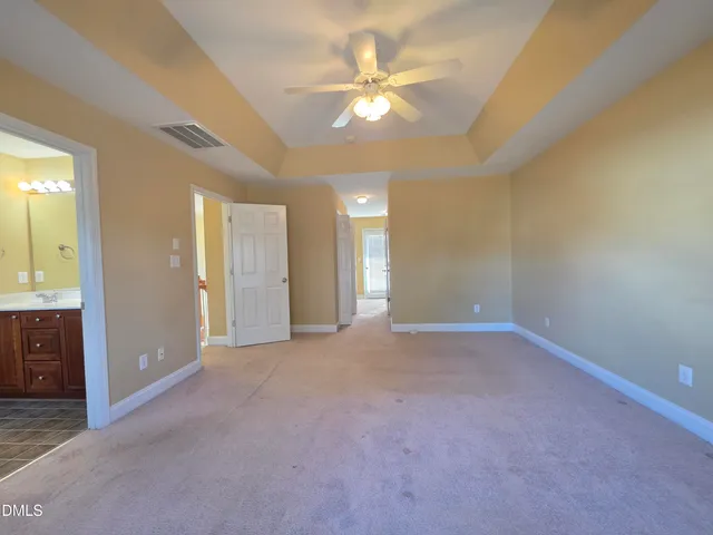 an empty room with a bathroom and a ceiling fan