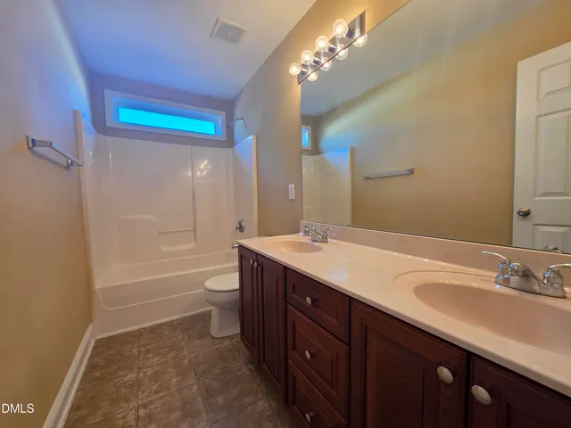 a bathroom with a double vanity sink a toilet and a shower