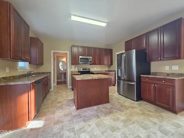 a large kitchen with stainless steel appliances granite countertop a refrigerator stove top oven and sink