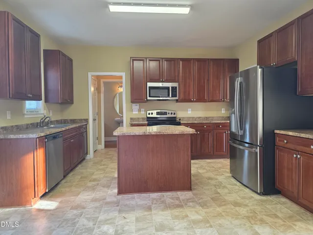 a kitchen with stainless steel appliances granite countertop a stove a refrigerator a sink a microwave and wooden cabinets