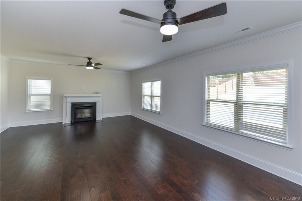 5810 Carmel Road Charlotte, NC 28226 - Photo 14 of 31 an empty room with wooden floor chandelier fan and windows