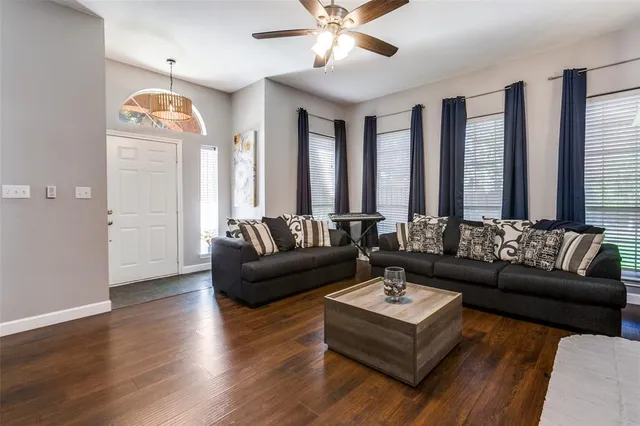 a living room with couches and a potted plant with wooden floor
