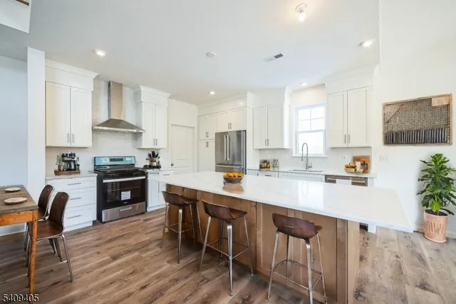 a kitchen with stainless steel appliances granite countertop a stove top oven a sink dishwasher a dining table and chairs with wooden floor