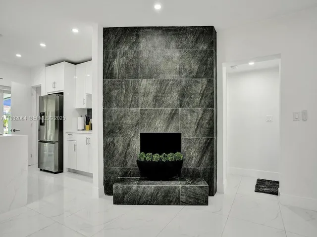 a living room with stainless steel appliances furniture a refrigerator and a fireplace