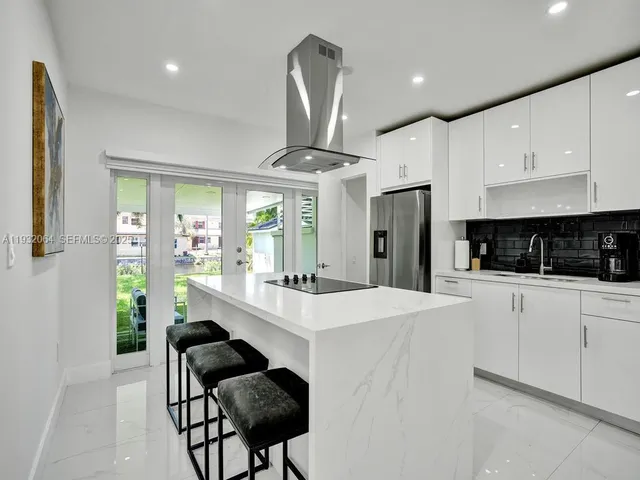 a large white kitchen with stainless steel appliances granite countertop a stove a refrigerator a oven a dining table and chairs with wooden floor