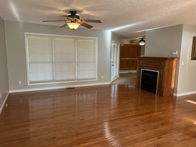 wooden floor in an empty room with a fireplace and a window
