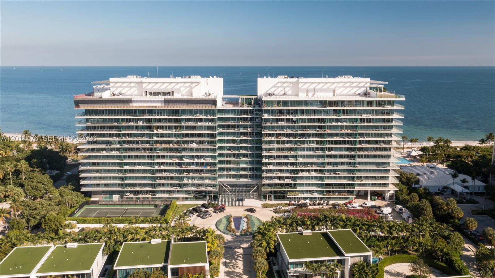 360 Ocean Drive, Unit 1106S Key Biscayne, FL 33149 - Photo 66 of 67 Aerial Building and Ocean View – A full aerial view presents the glass-fronted building with the ocean beyond and surrounding residences nearby. The composition captures the property’s modern architecture and coastal backdrop.