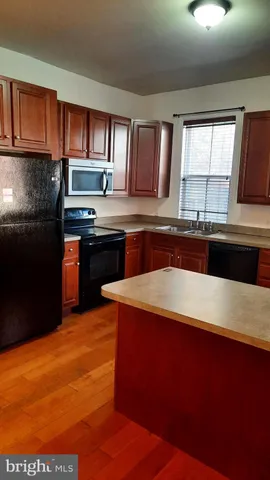 an empty room with wooden floor chandelier and windows