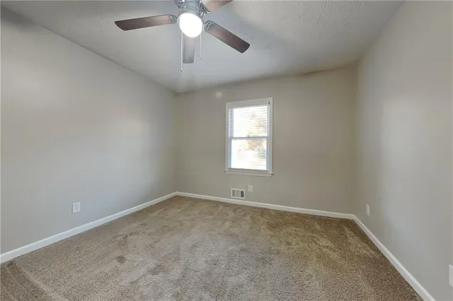 an empty room with a chandelier fan and windows