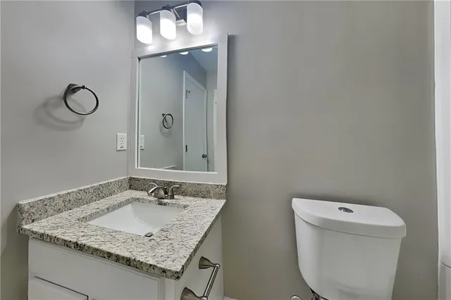 a bathroom with a granite countertop sink a toilet and a mirror