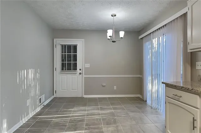 an empty room with chandelier fan and windows