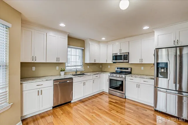 a kitchen with white cabinets stainless steel appliances and a sink
