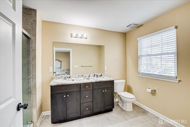 a spacious bathroom with a granite countertop toilet sink and mirror