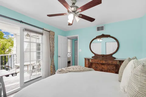 a bedroom with a bed a mirror on table and windows