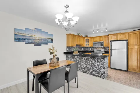 a kitchen with stainless steel appliances granite countertop a sink a stove a dining table and chairs