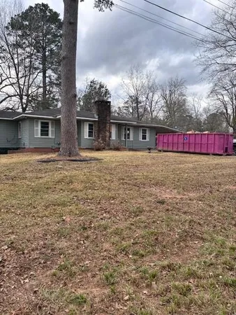 a view of a house with a yard and a large tree