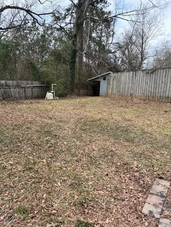a view of backyard with wooden fence and trees