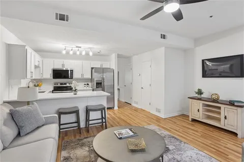 a living room with furniture a flat screen tv and kitchen view