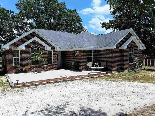 a view of a house with a yard and large tree