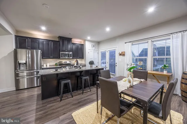 a kitchen with stainless steel appliances granite countertop a stove a refrigerator a kitchen island a table and chairs