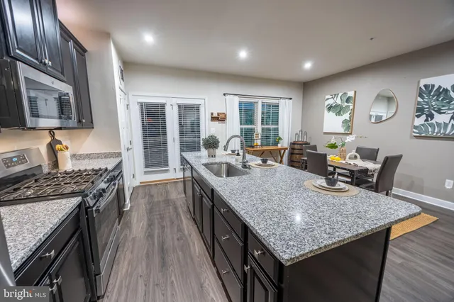 a kitchen with granite countertop stainless steel appliances and wooden floor