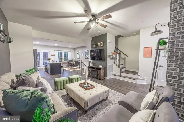 a living room with furniture kitchen view and a wooden floor